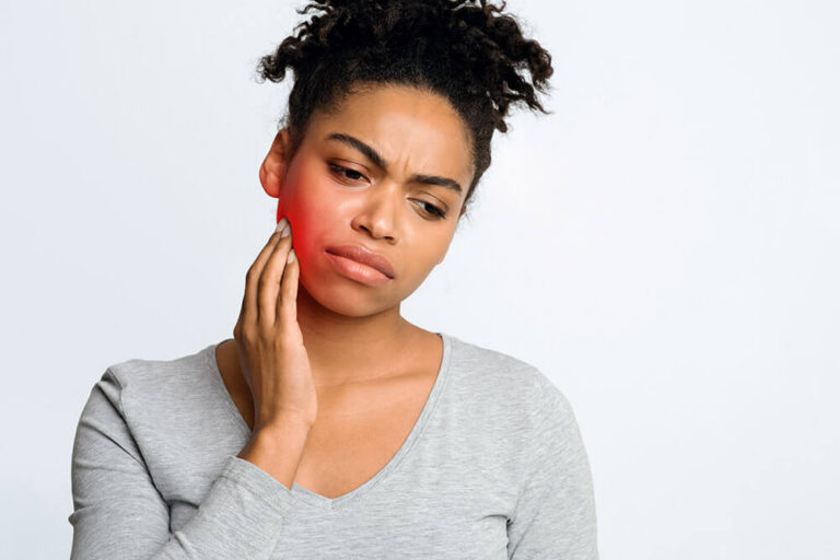 African American woman holding her jaw due to tooth ache and needs root canal